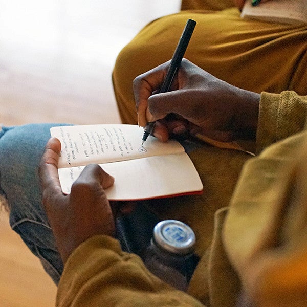 a person's hands writing in a notebook