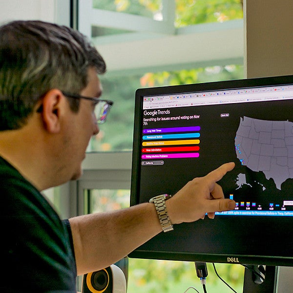 a person points at a computer screen showing a map of the US