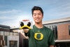 Travis Kim holds a UO360 cardboard viewfinder featuring the eyes and bill of the UO Duck mascot